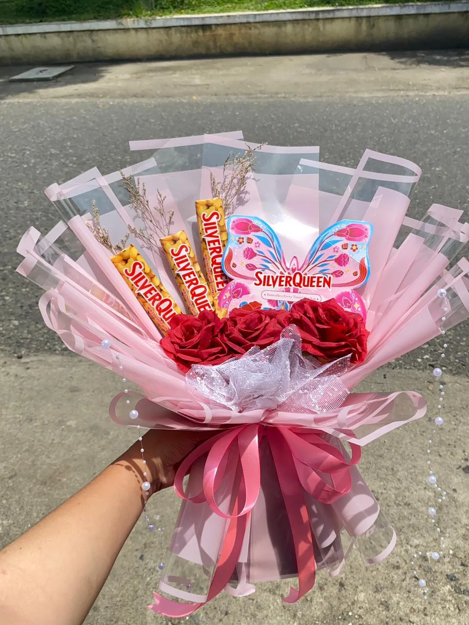 Buket snack berisi cokelat batang dan bunga merah